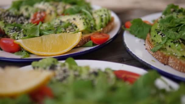 Zdravé stravování trendy v menu veganské restaurace. Tři porce avokádového toastu se salátem a citronem — Stock video