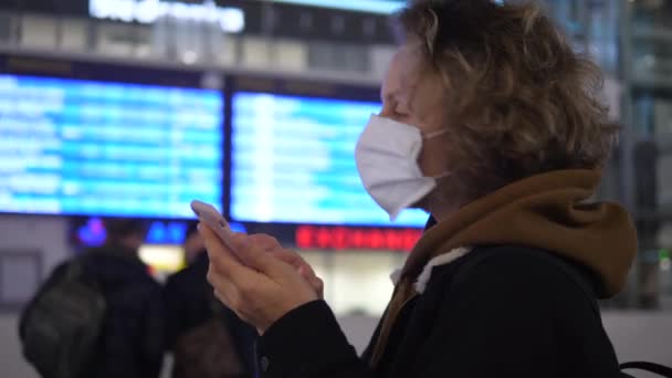 Öffentliche Verkehrsmittel während des Coronavirus-Ausbruchs. Maskierte Frau checkt Fahrplan mit Bordkarte am Telefon — Stockvideo