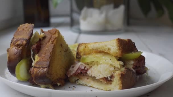 Белая тарелка с мясным сэндвичем с маринованными огурцами и капустой на боку для быстрого обеденного перерыва. Демонстрация рецептов от блогера gastro — стоковое видео