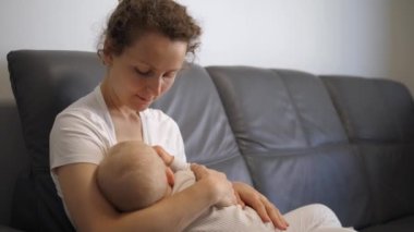 Annem evdeki kanepede küçük bir kızı emziriyor. Aile hayatı ve çocukların beslenmesi