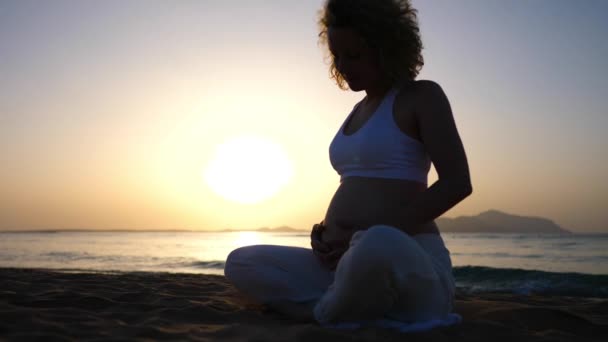 Esperando a una mujer meditando en la playa al atardecer. Disfruta del embarazo con práctica de mindfulness — Vídeos de Stock