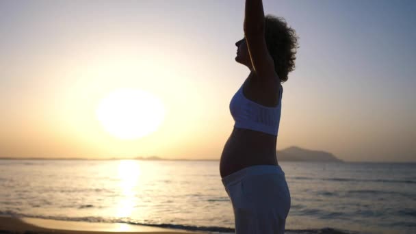 Glad mammaledighet på stranden. Vit gravid kvinna utövar solnedgång yoga vid havet — Stockvideo