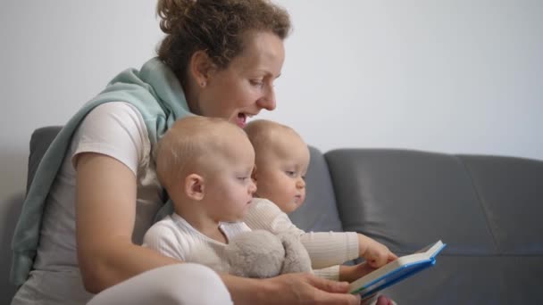Mãe leitura livro para seu bebê gêmeos na cama antes de ir dormir — Vídeo de Stock
