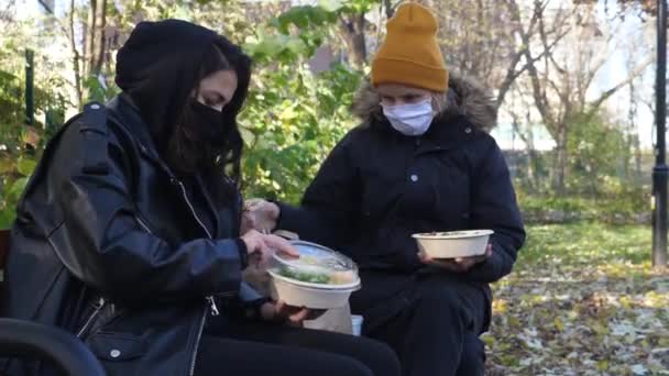 Dvě ženy v maskách mají oběd jít spolu ven během epidemie coronavirus. — Stock video