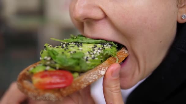 Rozmanitá středomořská kuchyně pro zdravotní přínosy. Veganka kouše zeleninový toust s avokádovými plátky a listovou zelení — Stock video