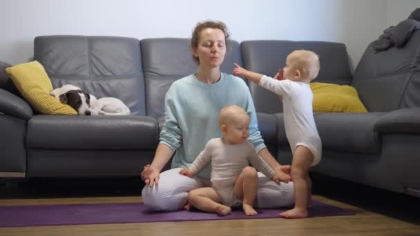 Self care and personal time of busy parents life. Single mom tries to meditate on yoga mat at home with two active kids around distracting her — Stock Video