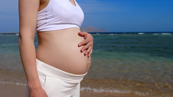 Familjesemester vid havet. Ung mor väntar barn snart njuta av solen på stranden — Stockfoto