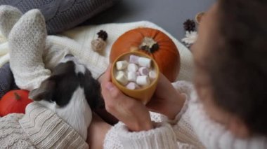Kötü havaya rağmen mutlu olmak için kucaklaşmak. Marşmelovlu matcha latte içen ve sıcak kazaklı evcil hayvan ev atmosferinin tadını çıkaran bir kadın.
