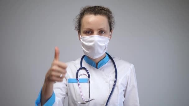 Råd från hälso- och sjukvårdssystemet vid pandemiutbrott. Tummen upp från kvinnliga läkare för att bära ansiktsmask för att skydda allmänheten från att fånga coronavirus — Stockvideo