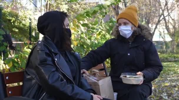 Femeie prietenă care poartă măști având prânzul împreună în aer liber în timpul pandemiei de coronavirus . — Videoclip de stoc
