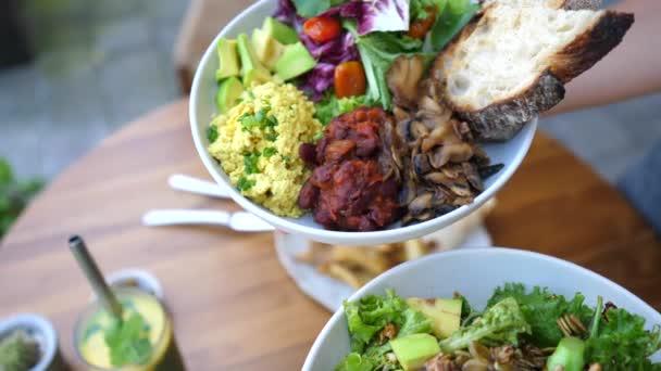 Handen presenteren twee veganistische maaltijden opties van boeddha kom en een salade gto de camera. — Stockvideo