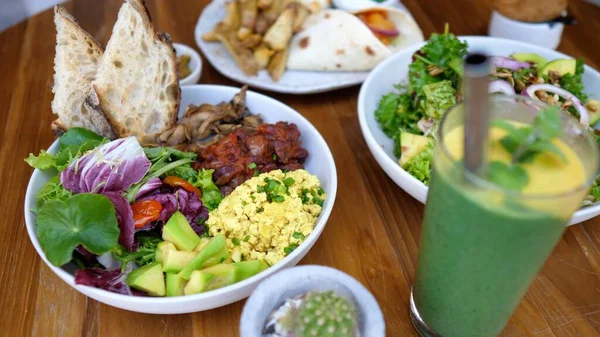 Vue de dessus du déjeuner végétalien de deux bols de bouddha, enveloppements, apéritifs et un smoothie vert servi sur une table — Photo