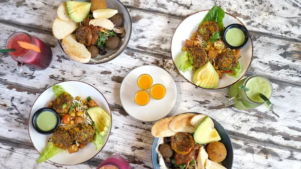 Top view of vegan meals and smoothies served on a rustic wooden table. Clean eating concept. — Stock Photo, Image