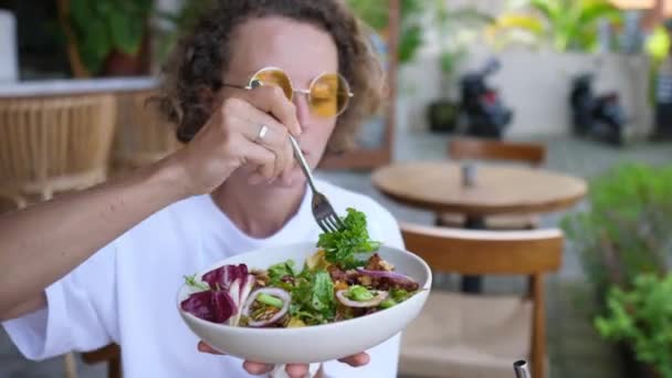 Clean eating diet. Young Caucasian woman eating a salad with satisfaction in an outdoor cafe — Stock Video