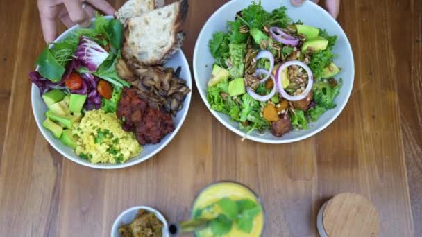 Mão servir dois pratos de pratos vegan deliciosos saudáveis sobre a mesa. Conceito de alimentação limpa — Vídeo de Stock