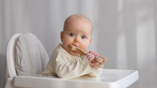 Mignon bébé fille assis dans la chaise haute et jouer avec jouet en bois Eco. — Photo