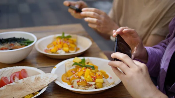 Två kvinnor tar bilder på sin vegan lunch med smartphones. Friska vegan livsstil koncept. — Stockfoto