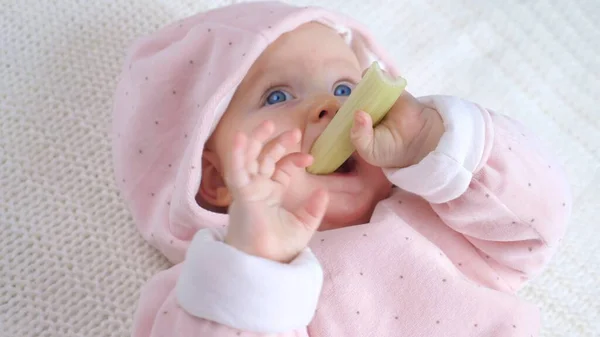 Bebé comiendo apio acostado en el suelo. —  Fotos de Stock