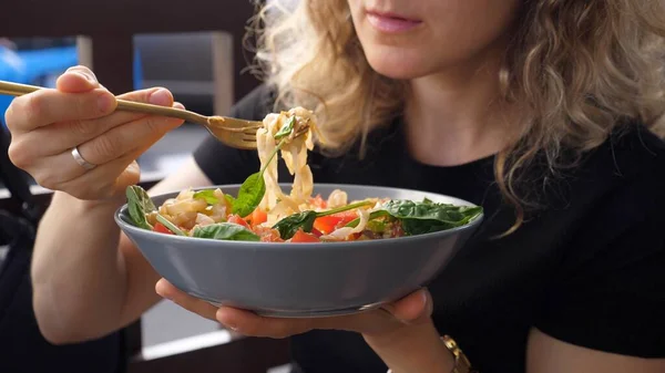 Närbild av lockigt blond flicka äter skål med pasta med stor aptit. Lunch i staden — Stockfoto