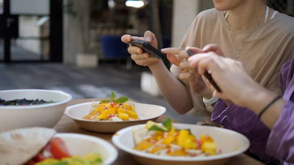 Voedselbloggen. Vriendinnen nemen foto 's van hun heerlijke en kleurrijke lunch voordat ze het eten. Technologie en cultuur — Stockfoto