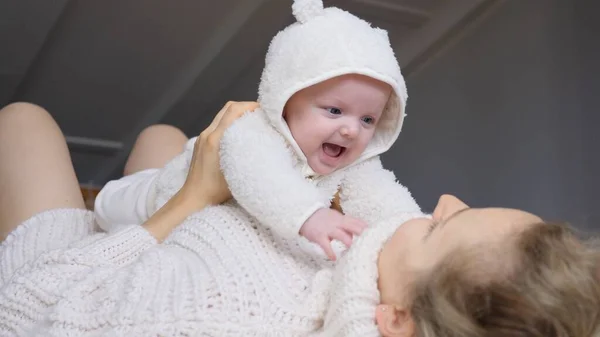 Junge Mutter spielt mit ihrem glücklich lächelnden Baby zu Hause. — Stockfoto