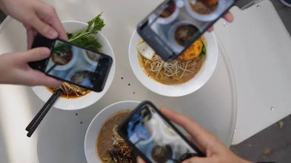 Gros plan de trois téléphones tirant des plaques blanches avec ramen végétalien à partager sur les médias sociaux. Spécialité restaurant asiatique — Photo