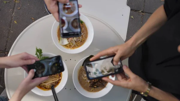 Aziatisch trendy straatvoedsel. Bovenaanzicht van handen die foto 's maken van smakelijke plantaardige noodle soep — Stockfoto