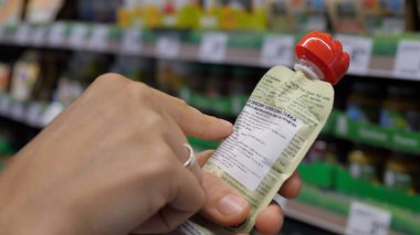 Markette etiket bilgilerini okumak için kadın ellerinin bebek ürünlerini tutması. Alışveriş konsepti