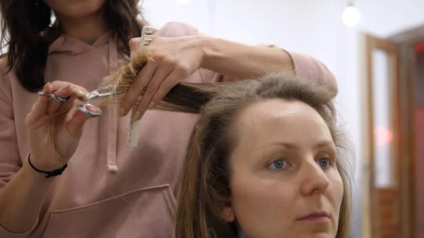 Peluquero cortando el pelo de una joven con tijeras y un peine. Bauty y servicios de salud —  Fotos de Stock