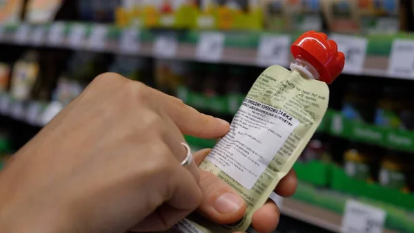 Markette etiket bilgilerini okumak için kadın ellerinin bebek ürünlerini tutması. Alışveriş konsepti