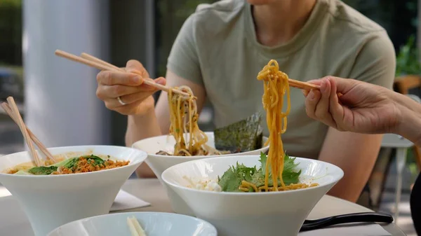 İki kız geleneksel Japon erişte çorbalarını içiyor. Arkadaşlar Asya lokantasında yemek yiyorlar.