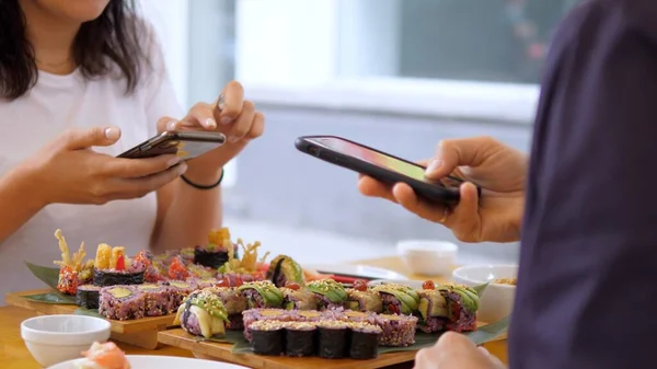 Bloguer sur la nourriture. Les filles prennent des photos de leurs sushis au déjeuner. Cuisine japonaise artisanale — Photo