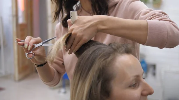 Spotkanie u fryzjera. Biała dziewczyna obcina włosy w salonie fryzjerskim. Koncepcja samoopieki i urody — Zdjęcie stockowe