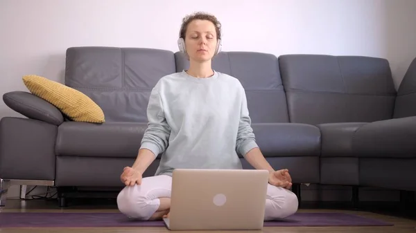 Restrições de bloqueio do Coronavirus. Visão frontal da mulher caucasiana praticando meditação guiada em casa online. — Fotografia de Stock