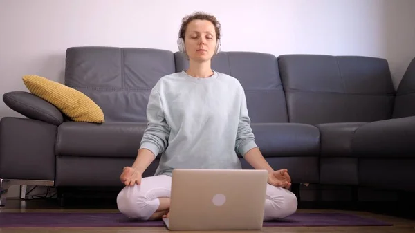Coronavirus kilitleme kısıtlamaları. Kafkasyalı kadının evde online meditasyon uygulamasını ön planda tutmak.