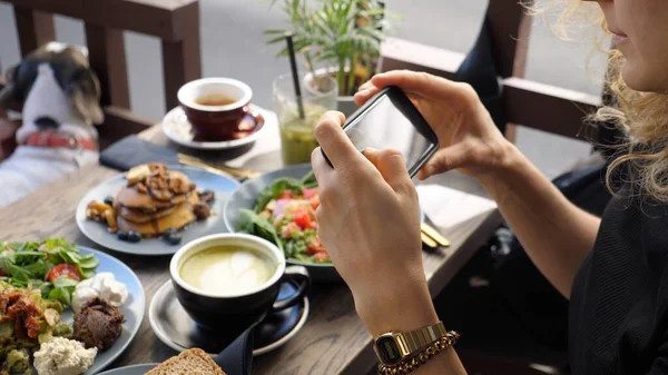 Fille prenant des photos de brunch végétalien sain dans le café de la ville avec smartphone. Concept de blogging alimentaire — Photo