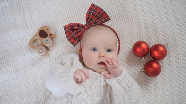 Babykläder stickad tröja och röd rosett firar jul. — Stockfoto