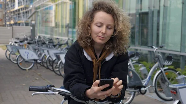 Mobilidade urbana sustentável. Jovem mulher verificando bicicleta de transporte público compartilhamento aplicativo smartphone — Fotografia de Stock