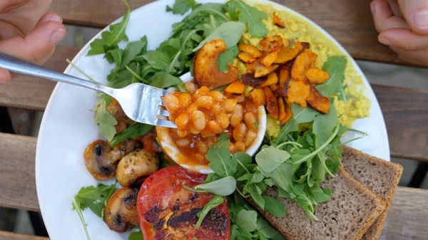 Beyaz tabakta servis edilen vejetaryen kahvaltısının üst görüntüsü. Soya peyniri, mantar, fasulye, kepekli ekmek ve sebze. Sağlıklı vejetaryen yaşam tarzı kavramı