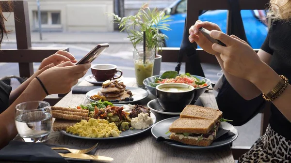 Almoço hipster saudável na cidade. Dois amigos blogueiros de comida tirando fotos de sua comida com smartphone. — Fotografia de Stock