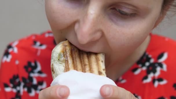 Mulher com fome em roupas coloridas comendo wrap sanduíche. Feche em cima de uma boca de mascar. Tirar o conceito de comida — Vídeo de Stock