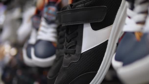 Gros plan des baskets noires et blanches suspendues dans la section chaussure du magasin de sport. — Video