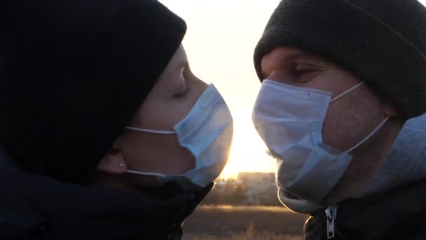 Giovane coppia che indossa maschere protettive per il viso e baci all'aperto. — Video Stock