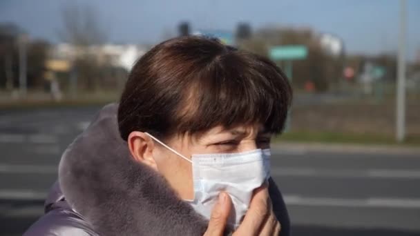O femeie în vârstă bolnavă care poartă mască de față și tuse în aer liber. Coronavirus, Concept de pandemie de gripă . — Videoclip de stoc