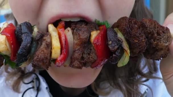 Hungrig kvinna biter vegan BBQ med sojakött och grönsaker från spett. Friska växtbaserade gatumat — Stockvideo