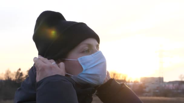 Młoda kobieta odkłada maskę na twarz i oddycha głęboko na zewnątrz. — Wideo stockowe