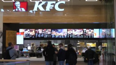 KFC müşterilerinin, koruyucu yüz maskeleriyle sosyal mesafeyi gözlemledikleri bir ön görünüm. Covid 19 salgını sırasında fast-food restoranı. Varşova-Polonya-2020.