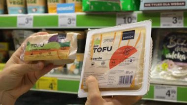 Biyolojik tofu paketlerini tutarak malzemeleri okumak için iki elinizi yakın tutun. Market alışverişi konsepti. Varşova-Polonya-2020