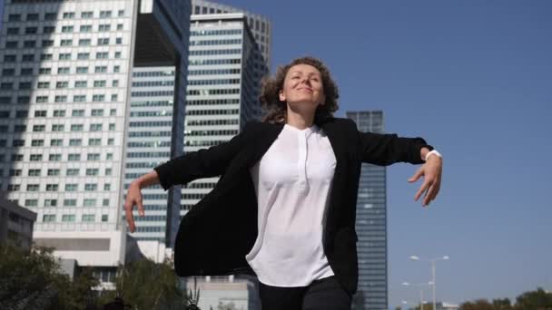 Aufgeregte Dame in formeller Bürokleidung, die vor Wolkenkratzern ihre Beförderung feiert — Stockvideo
