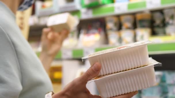 Comprando comida. Primer plano de la hembra sosteniendo muchos productos en paquete de plástico en la tienda de comestibles para comprobar el contenido — Vídeo de stock